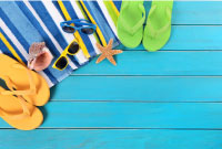 photo of bright coloured summer sandals, glasses and swim towels